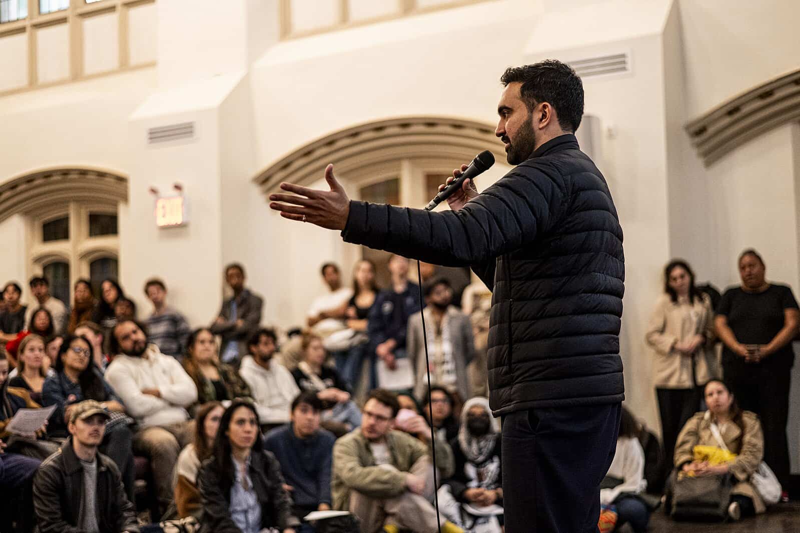 Zohran Mamdani speaking in front of a crowd, using a message of populism