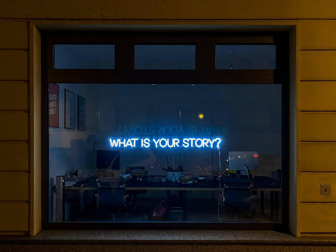 What is your story? sign illuminated in an office window
